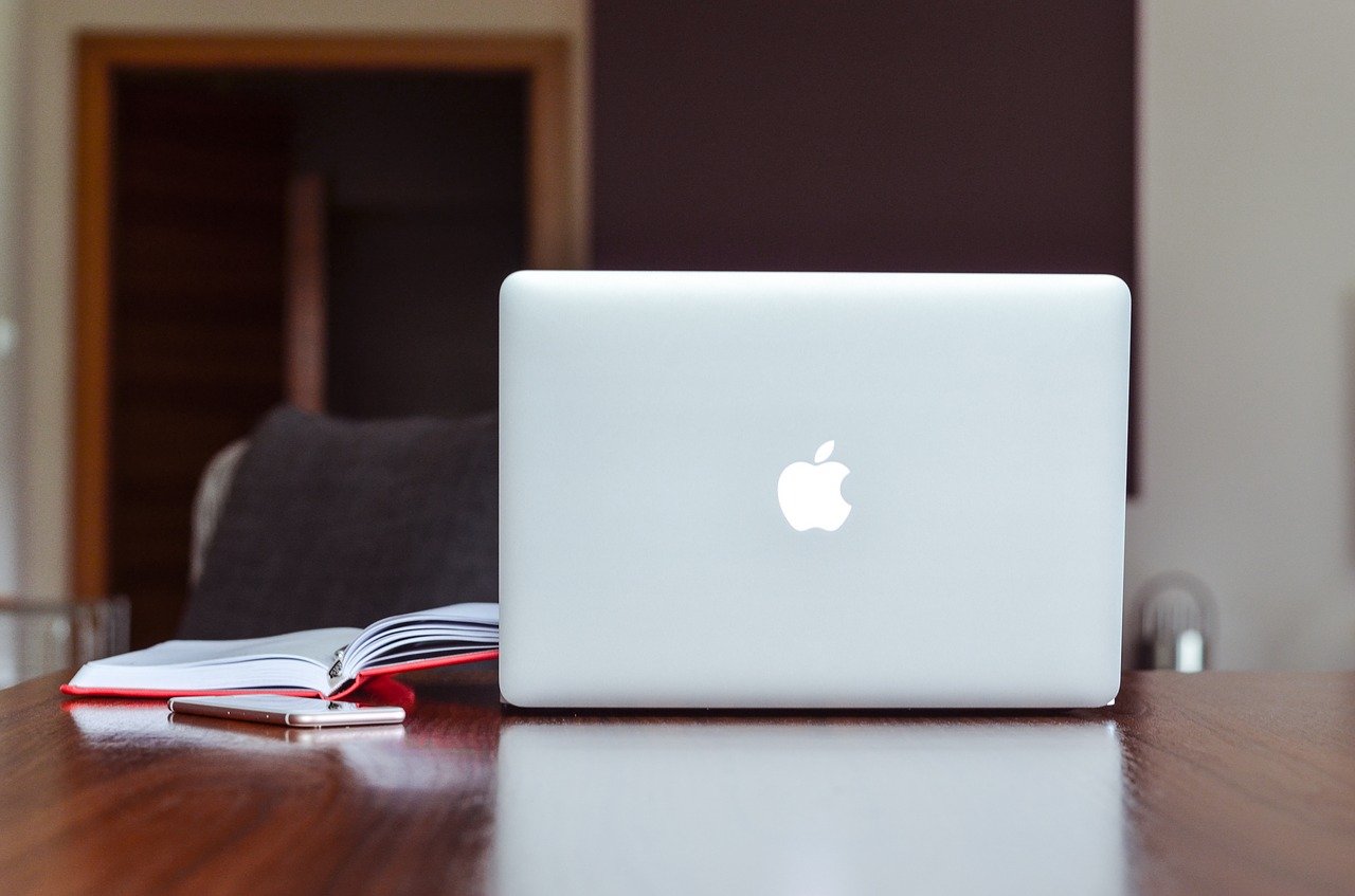 MacBook on a table with a book and a smartphone